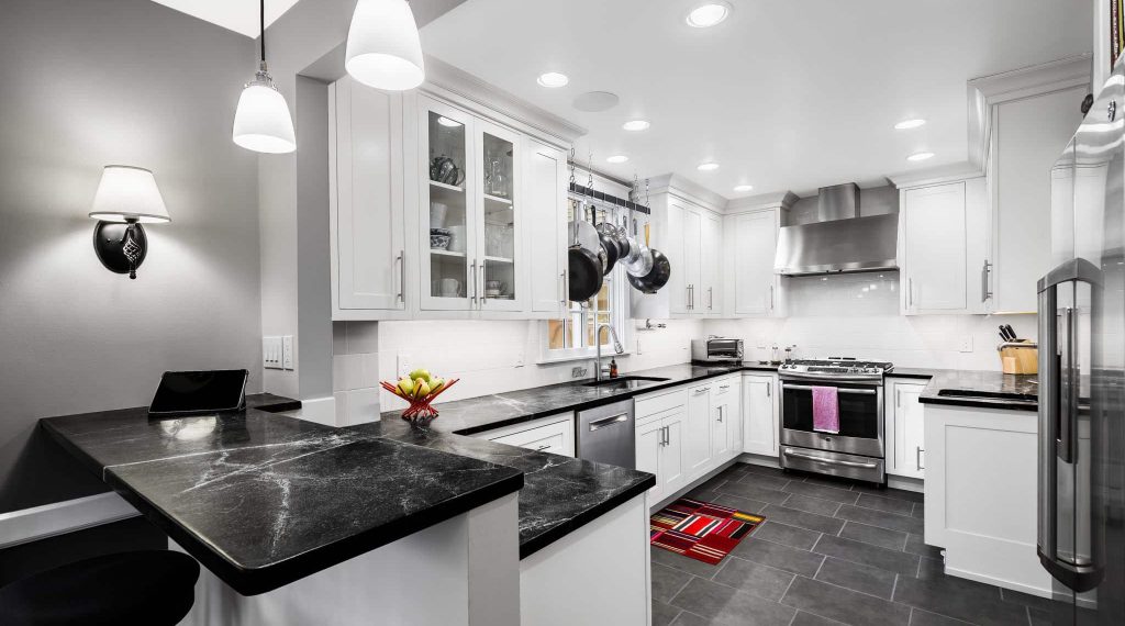 Black and white kitchen in Ardmore, PA designed in Bishop cabinetry with New Ashford inset doors, soapstone countertops, and a two-tiered peninsula with countertop seating.