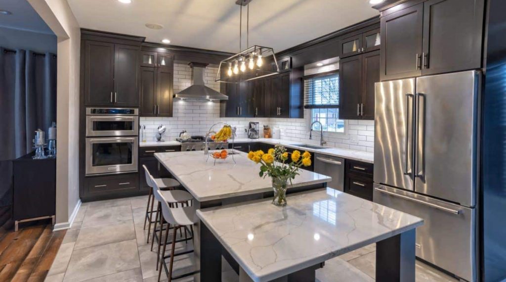 Modern kitchen designed by Main Line Kitchen Design in Philadelphia, PA with coffee colored cabinetry and white quartz countertops with a split level kitchen island.