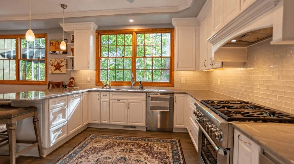 White kitchen in Ardmore, PA featuring an antique rug and a window over the sink framed in natural wood
